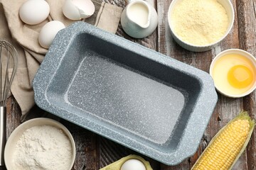 Making cornbread. Baking dish, different ingredients and whisk on wooden table, flat lay
