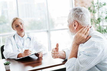 Patient Discussing Neck Pain With Doctor During Consultation in a Bright Medical Office