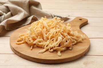Dried squid shavings on light wooden table, closeup