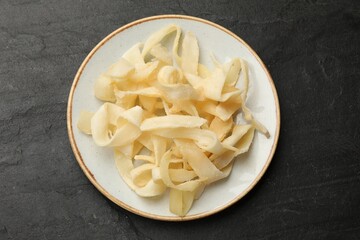 Tasty dried shredded squid on black table, top view