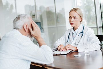 Fototapeta premium Senior patient visiting physician for a consultation in a hospital office discussing symptoms for accurate diagnosis