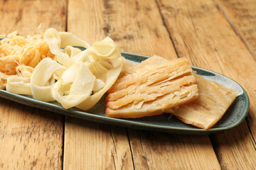 Different tasty dried squid on wooden table, closeup