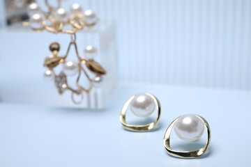 Stylish gold earrings on light blue background, closeup. Space for text