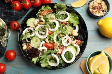 Delicious squid salad and ingredients on light blue wooden table, flat lay