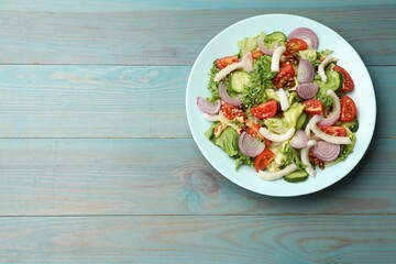 Delicious salad with squid, vegetables and walnuts on light blue wooden table, top view. Space for text