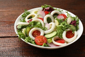 Delicious salad with squid rings and vegetables on wooden table, closeup