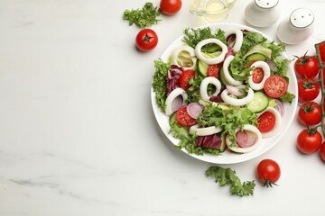 Delicious salad with squid rings and vegetables served on white marble table, flat lay. Space for text