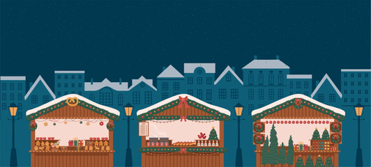 wooden stalls at Christmas market in city at night with festive lights, gingerbread, mulled wine, hot dogs and snowy atmosphere