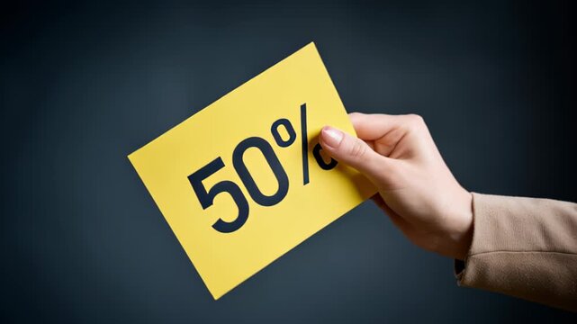 Close-up of female hands holding yellow card with 50 percent discount. Big sale. 