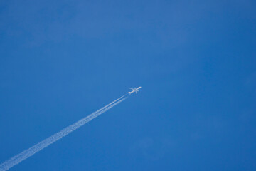a passenger plane in the blue sky leaving traces behind