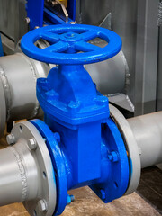 Blue industrial valve installed on a large pipe in a factory setting during daytime