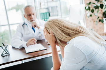 Obraz premium Woman in distress consulting a professional physician in a well-lit clinic office during a medical consultation for health issues