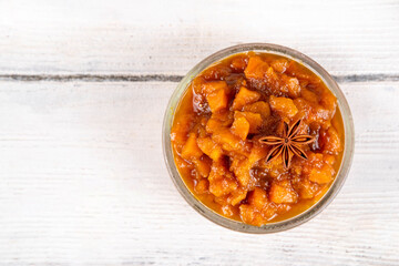 Homemade sweet autumn Pumpkin Chutney, with brown sugar, cinnamon, on white wooden background with ingredients for cooking - pumpkin squash, spices, honey