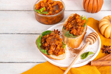 Tasty autumn toast sandwiches with spicy pumpkin chutney and spinach, healthy snack idea for fall brunch