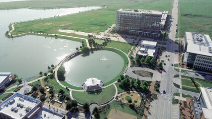 Circular pond with white pavilion, surrounded by North Lake trails, restaurant patios, office buildings along Cypress Waters Boulevard, showcasing entertainment and waterfront lifestyle in Dallas
