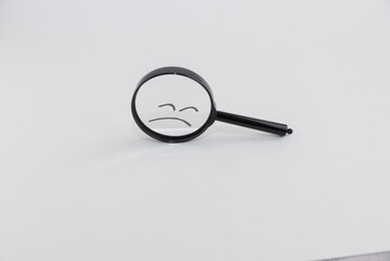 A sad face in a magnifying glass. Sad emotions and the concept of mental health care