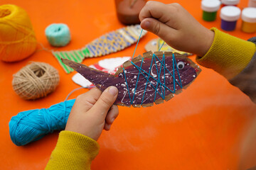 Create a fish figure from cardboard, thread, and paint, with a detailed guide, on an orange background.