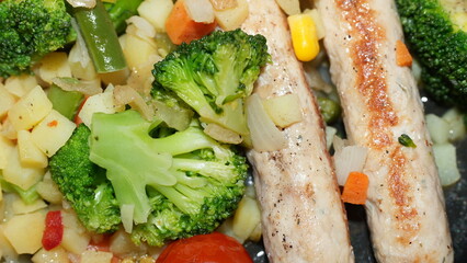 Close-up of healthy meal with grilled chicken breast and fresh vegetables including broccoli, carrots, corn and beans, concept of clean eating and balanced diet
