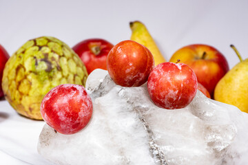 tres ciruela roja y maduras., las mas buenas con fondo blanco y frutas variadas encima de un bloque de sal