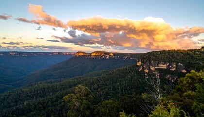 Scenic vista of lush, forested valley below a clifftop, with colorful clouds above
