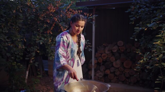 Woman frying baursaks in outdoor cauldron