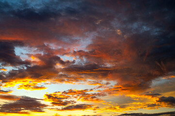 Cumulus sunset clouds with sun setting down on dark background.orange cloud sky and blue sky. Beautiful sky.