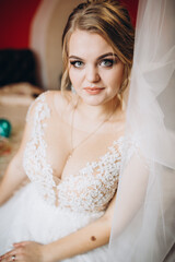 Fototapeta premium Bride in lace wedding dress with veil smiles. Her joyful expression radiates happiness and love on her wedding day.