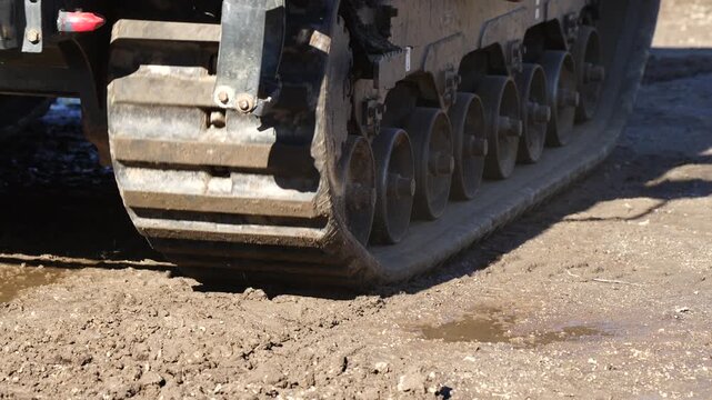 Tracked undercarriage of heavy construction machinery pressing into soil showing durable rubber-steel track system, ground pressure distribution and engineering design for traction stability