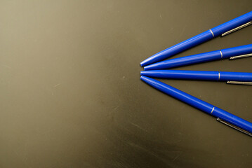Ballpoint pens of blue color on black ie. dark background