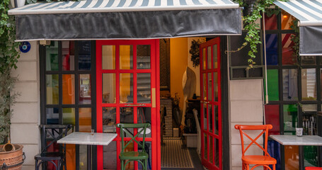 A charming cafe's open red doors invite passersby into a cozy, eclectic interior, while outside,...