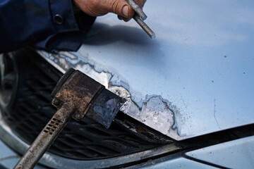 Car body shop. Repair man processes the welding seam using an angle grinder on replaced car part. Professional Body master grind old paint and rust. Rust damage. Rusting car. Hands with tool close-up