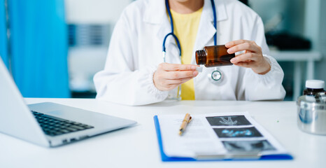 Asian female doctor examining medicine bottle in hospital office. Concept of healthcare,...