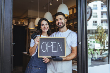 Open Sign Moment: Happy Couple Owners Welcome Guests at Cozy Local Coffee Shop