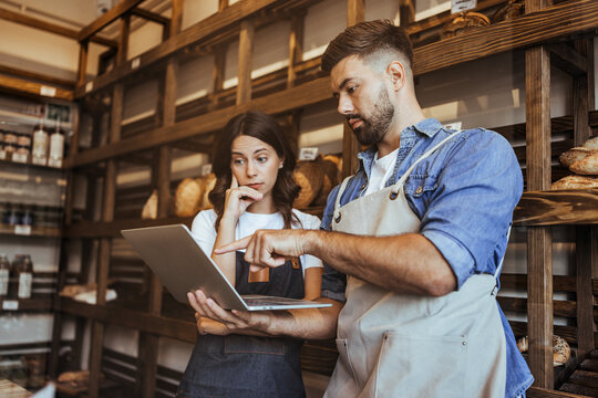 Two Bakers Collaborating Over Tablet in Bakery Shop, Discussing Business and Growth