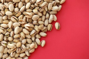 Tasty unpeeled pistachios on bright red background, top view flat lay background pattern