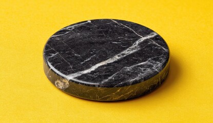 Round black marble coaster on yellow background