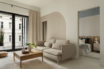Contemporary living room with beige sofa, wooden coffee table and large window with curtains.