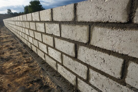 Fototapeta Murowanie fundamentu z widocznymi bloczkami i równą zaprawą. Solidna i staranna praca murarska na placu budowy, podstawa trwałej konstrukcji.
