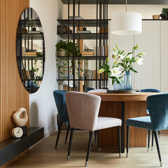 Stylish composition of elegant dining room interior design with velvet armchairs, design rouded wooden table and beautiful personal accessories. Glamour interior design inspiration. Template.