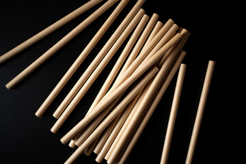 Stacks of wooden dowels arranged on a black surface in an artistic display for crafting or construction projects