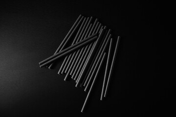 Stacked black straws on a dark surface in a minimalistic arrangement during evening hours