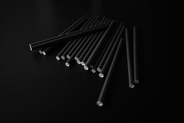 Many black and white sticks scattered on a dark surface creating a simple artistic arrangement