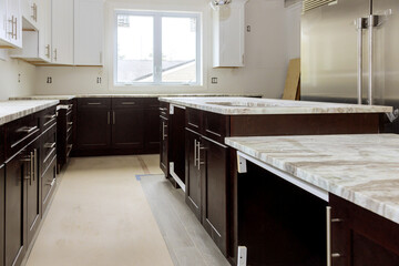 Construction is in progress in modern kitchen with dark cabinets chic marble countertops.