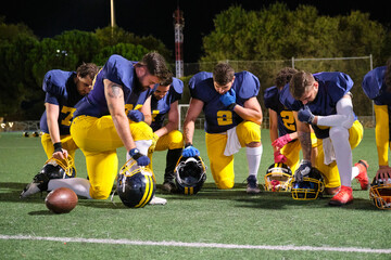 American football players kneeling, showing respect and focus before a game