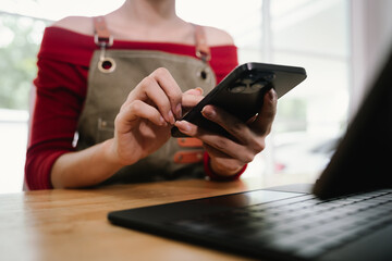 A person checking inventory with a tablet and notebook in a warehouse, surrounded by stacked cardboard boxes for shipping and logistics.