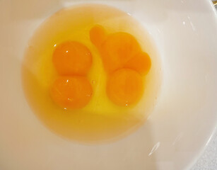 Golden twin egg yolks dance in porcelain bowl, harbingers of fertility festivals, culinary legerdemain, spring equinox mystery