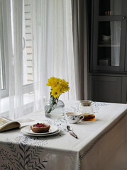 Sunlight dances through lace curtains onto a cozy breakfast nook, perfect for a serene Hygge celebration or Golden Week escape
