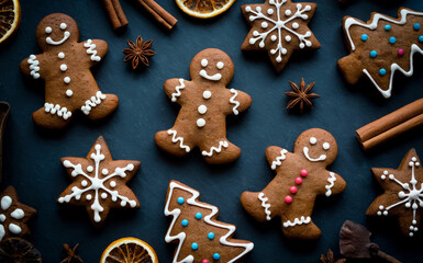 Christmas Gingerbread Cookie Display Featuring Snowflakes, Trees, Candy Dots, Dried Oranges, Cinnamon Sticks, and Star Anise, Festive Holiday Treats with Icing Details on Dark Surface