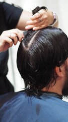 Fototapeta premium Hairstylist attaching a new capillary prosthesis to a man's head sitting on a salon