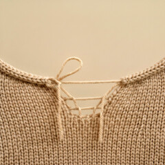 Obraz premium Close-up of a knitted beige sweater with a lace-up neckline, creating a cozy and warm feel, perfect for winter fashion and textile textures, showcasing detailed craftsmanship and design .